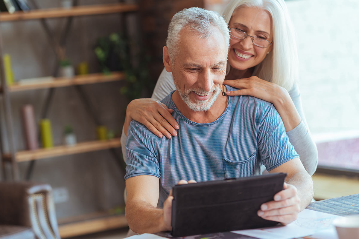 Smiling husband and wife enjoy Aristotle High Speed Internet Wi-Fi on a tablet device